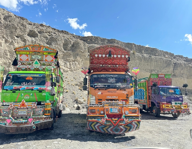 Decorated trucks parked against a rocky hill.