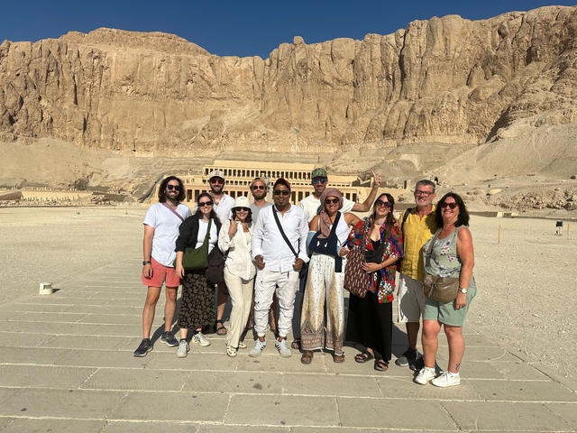 Group standing in front of an ancient temple carved into a cliff.