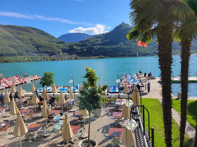       Outdoor dining area by a lake with parasols and boats.
  