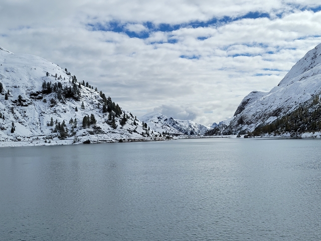       Snow-covered mountains and a calm lake beneath cloudy skies.
  
