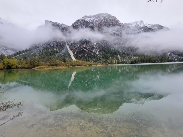       Scenic view of a clear lake reflecting mountains with clouds.
  