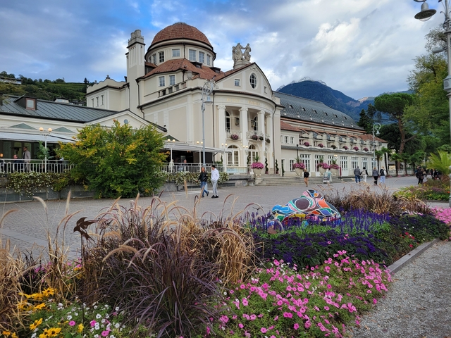 Large elegant building with people around, colorful flowers.