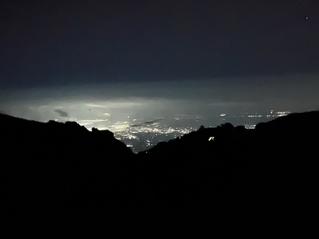 A distant view of city lights at night from a mountain.