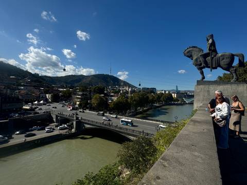      A scenic cityscape with a statue and river.
  