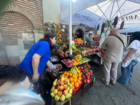       A busy fruit market with people browsing.
  