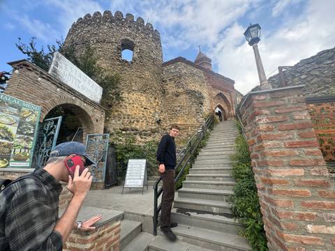       People entering a historic stone gate.
  