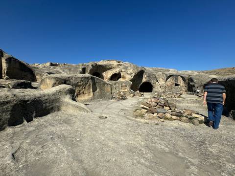      A man walking through an ancient cave site.
  