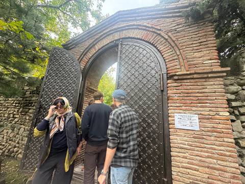       People entering an arched stone gate
  