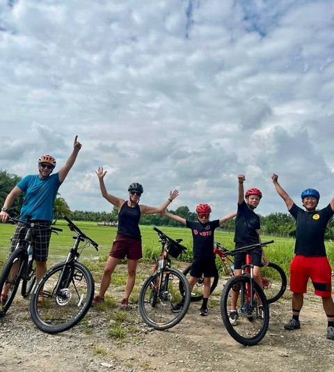       Group of cyclists celebrating with raised arms.
  