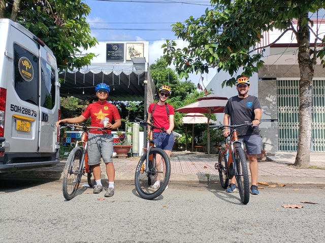       Group of cyclists posing with bikes.
  
