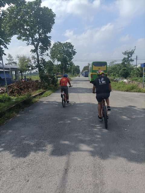       People cycling on a back road.
  