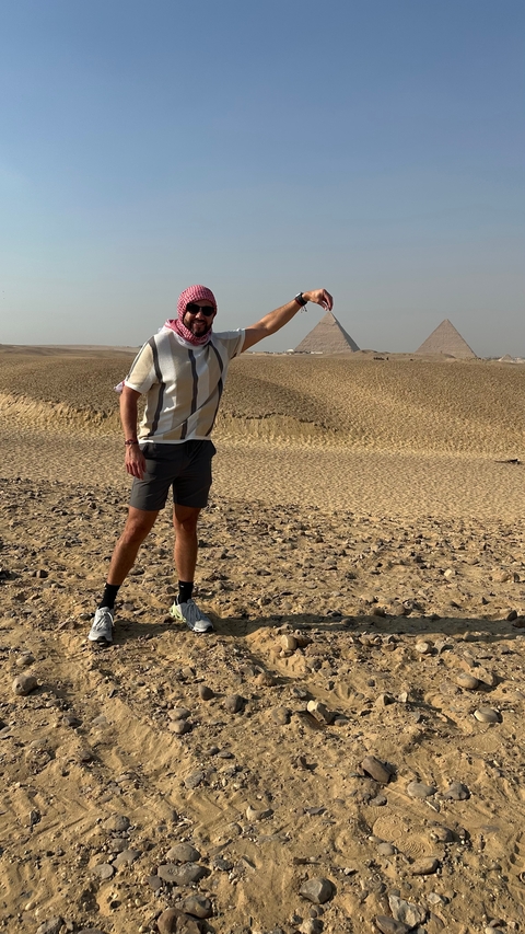 Person posing in front of the pyramids.