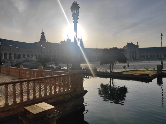 City square with reflective pool and sunlight.