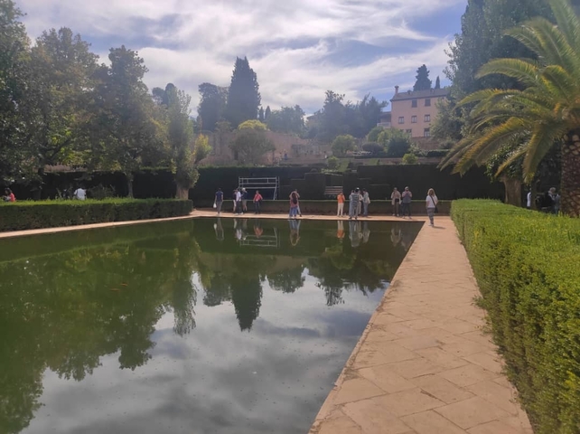       Garden with a reflecting pool and people walking.
  