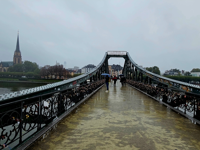Pedestrian bridge with people walking in rainy weather.