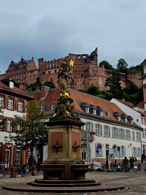 Statue with a historic castle in the background.