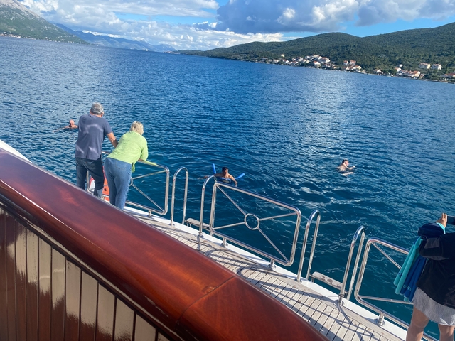       People swimming next to a yacht in clear waters.
  