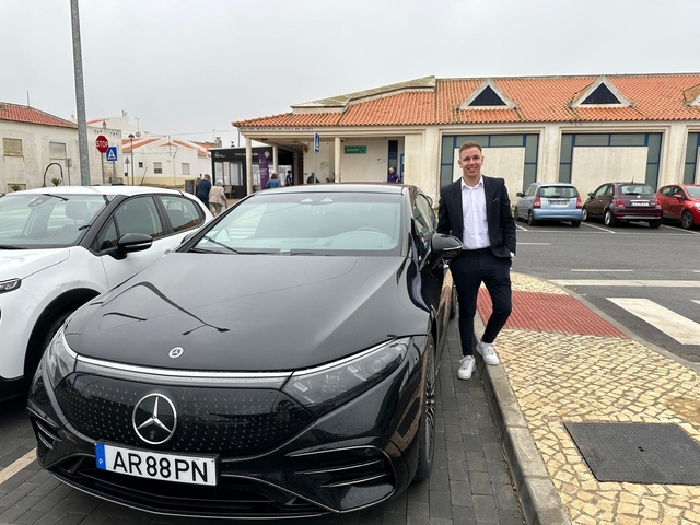 Person standing beside a car parked on a street
