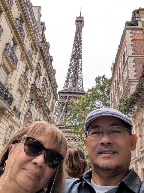Two people posing in front of the Eiffel Tower with surrounding buildings