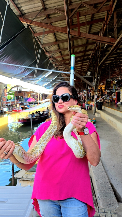 Person holding a snake at a floating market.