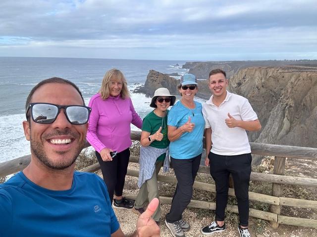 Group of people posing on a cliffside with an ocean view in the background.