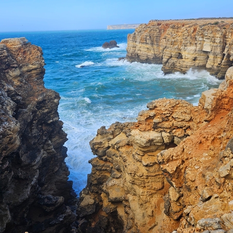 Close-up of rugged cliffs with ocean waves in the background.