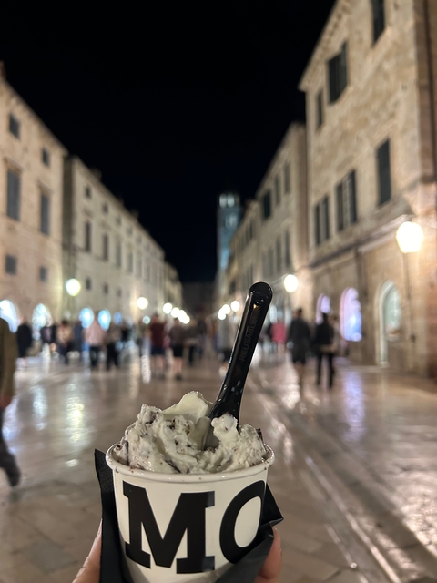       City street at night with blurred lights in the background and ice cream in focus.
  