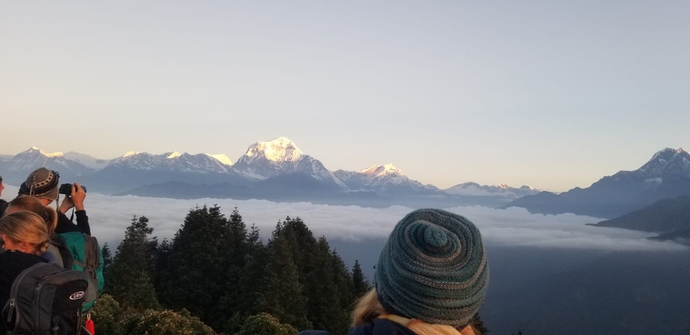 Tourists viewing snow-capped mountains above a sea of clouds