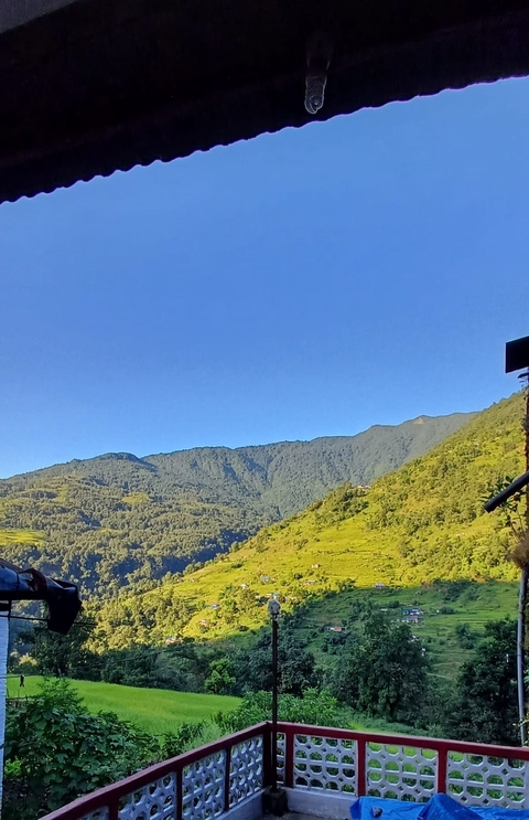 Rolling green hills and mountains under a clear blue sky
