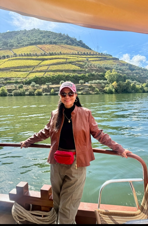 Woman on a boat with a landscape of vineyards in the background.