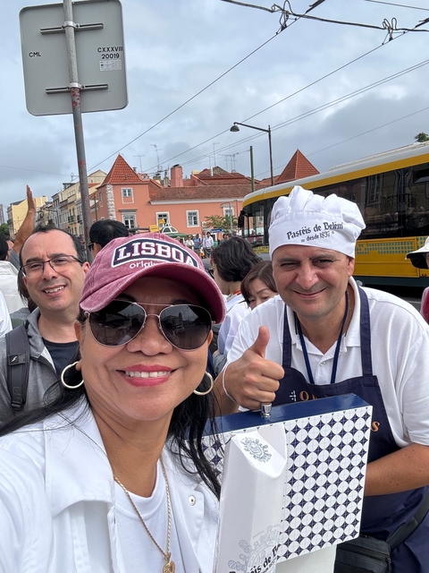 Woman in a hat with a baker standing in front of colorful buildings.