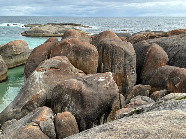 Smooth boulders by the sea with clear water.
