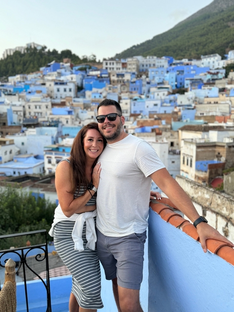 Couple posing with a wide view of blue and white buildings.