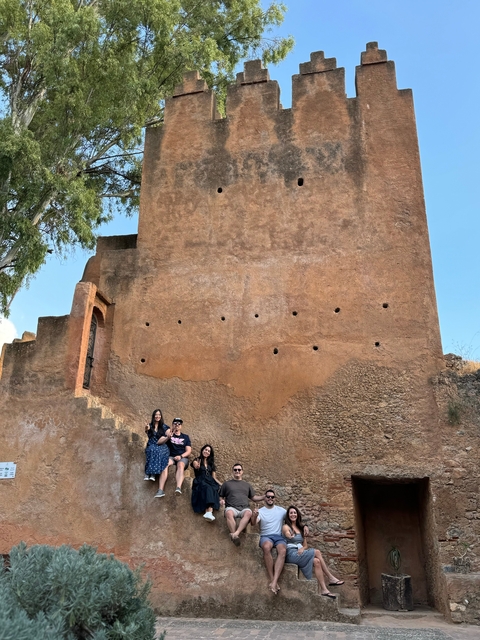 People posing in front of a large adobe structure.