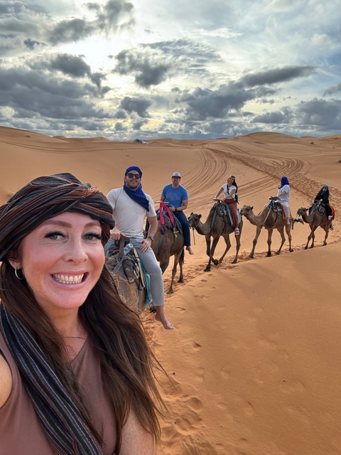 Selfie of a group riding camels in the desert.