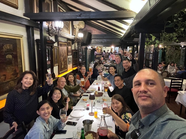       Group enjoying a meal at a restaurant, raising glasses.
  