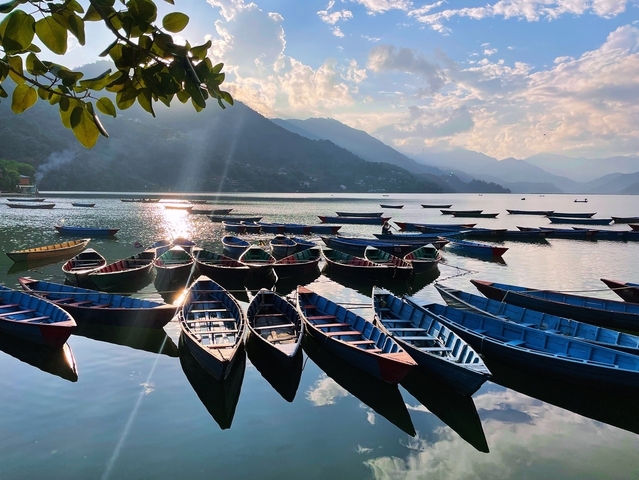 Boats lined up on a lake with mountains in the background.
