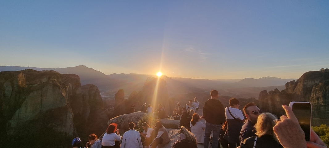       Group of people watching sunset over the mountains.
  