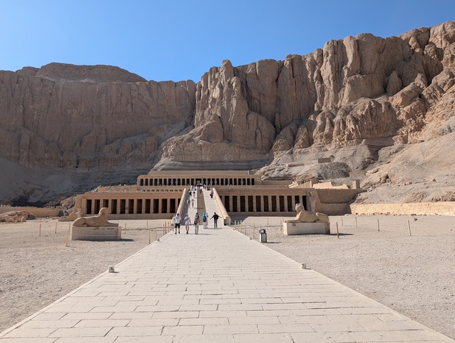 Temple in a mountainous desert area with people walking.