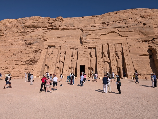 People visiting an ancient temple carved into a rock face.