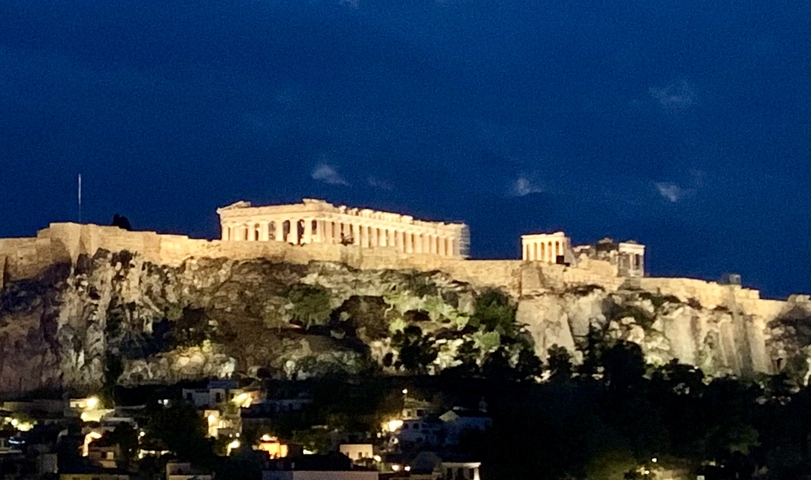 Night view of the Acropolis illuminated on a hilltop.