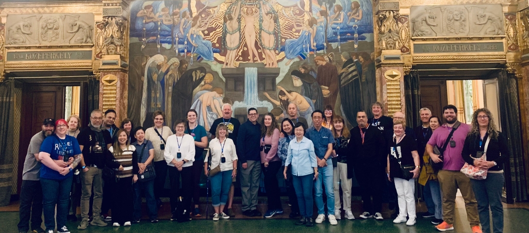 Group photo of tourists in front of a large mural