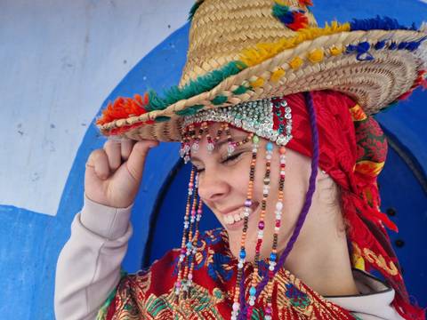 A person wearing a traditional hat and colorful attire, smiling.