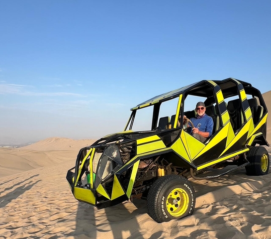       Man in a dune buggy on sand dunes.
  