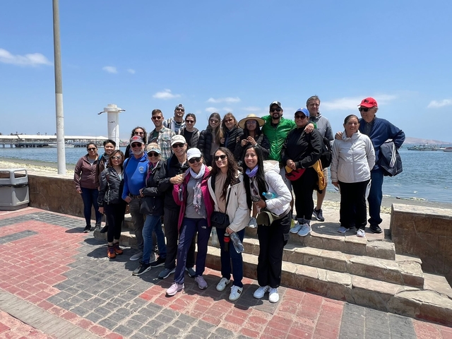       Large group of people posing by the water.
  