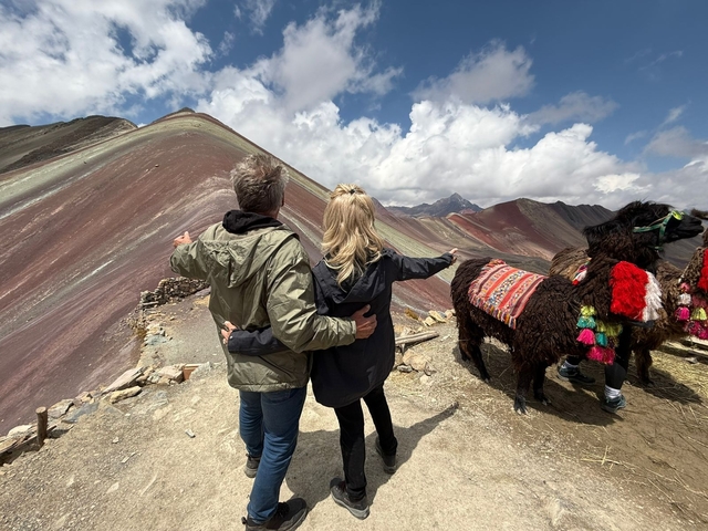       Couple admiring the view with a colorful llama by their side.
  