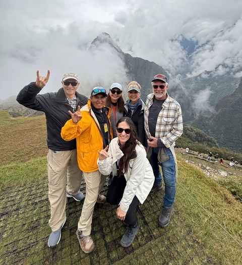       Group of smiling people posing in front of Machu Picchu.
  