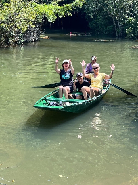 A group of people enjoying a boat ride on a river, waving happily.