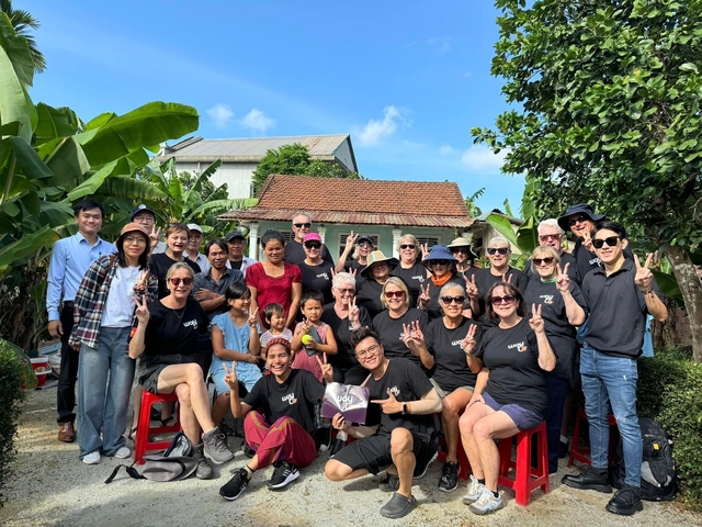 A large group of people posing for the camera in a garden setting.