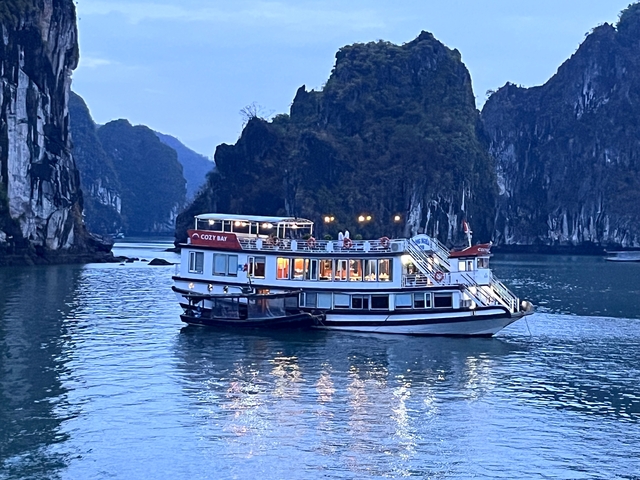       A cruise boat sailing through a scenic bay at dusk.
  